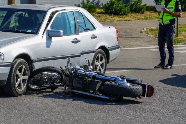 traffic accident, motorcycle collision with a car on city street